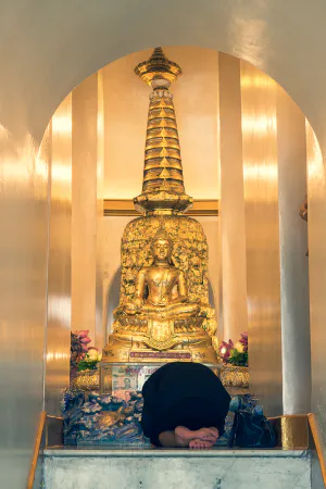 Woman bowing down on knees in Wat Saket