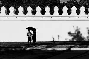 Silhouettes standing under same umbrella