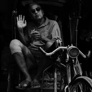 Shade-wearing man sitting on bike taxi