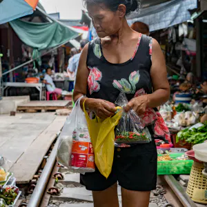 Woman walking on railroad track in Maeklong Railway Market