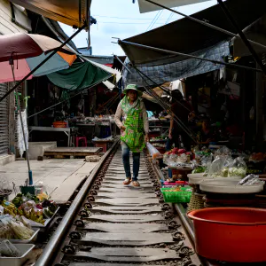Woman walking on railroad with plastic bag