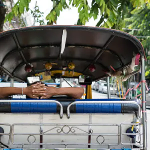 Man resting in the back seat of a tuk-tuk