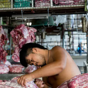 Young butcher cutting pork