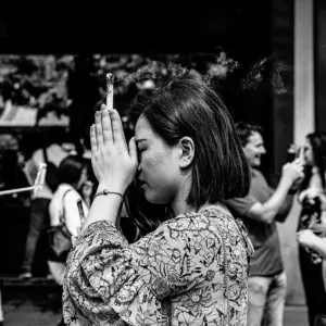 線香を握ったままお祈りする女性