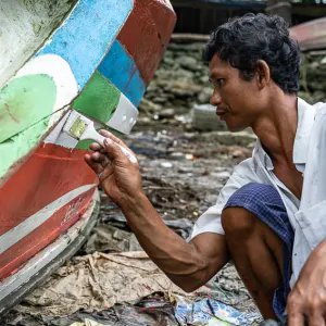 Man recoloring fishing boat