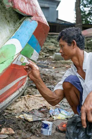 Man recoloring fishing boat