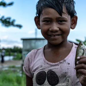 Girl holding small fish in her hand