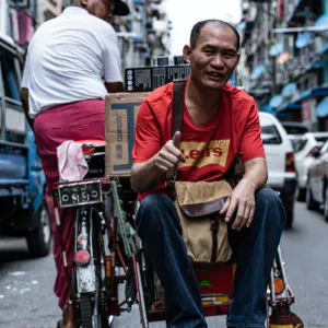 Man thumbing up on seat of pedicab