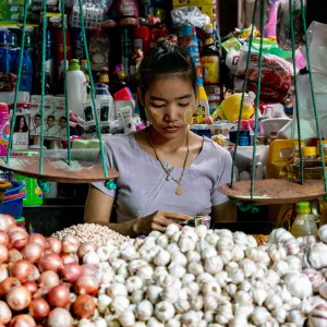 Woman working on the other side of pile of garlic