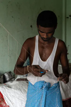 Man repairing fishnet with razor