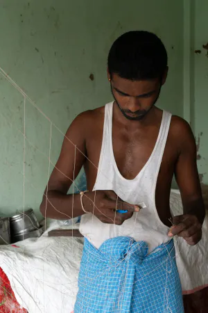 Man repairing fishnet with razor