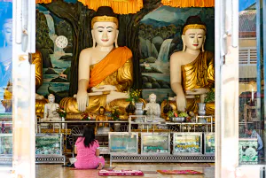 Woman sitting in front of many Buddha statues