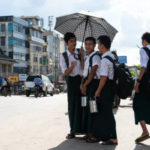 Schoolboys waiting for bus by roadside