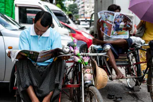 Pedicab drivers reading tabloid newspaper