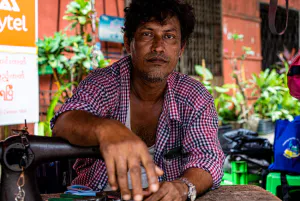 Man resting with his arm put on sewing machine