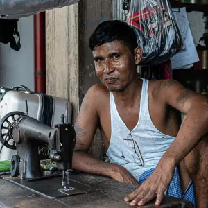 Man wearing tank top and sewing machine on table