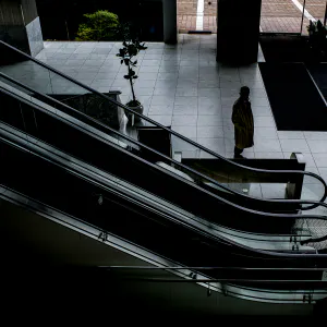 Man with a coat standing beside escalator