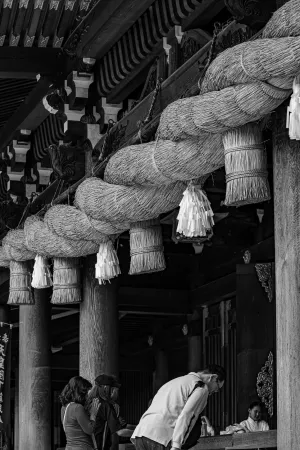 寒川神社の太い注連縄の下でお辞儀する男