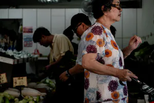 Older woman passing by vegetable section stately