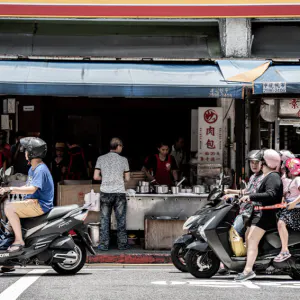 Motorbikes waiting at traffic light in front of shop