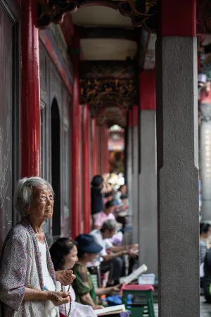 Older woman standing with beadrolls in her hands in Lungshan Temple