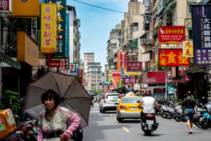 Older woman walking with umbrella near Bailan Market