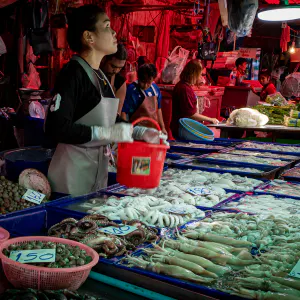 Young woman selling squid, octopus, and shell in Khlong Toei Market