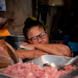 Female butcher taking a nap in Khlong Toei Market