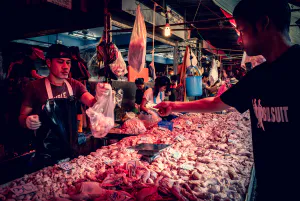 Man buying meat in a butcher in Khlong Toei Market