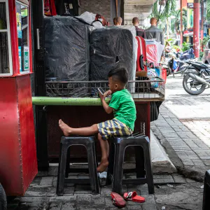 Boy watching the phone screen in Pasar Baru