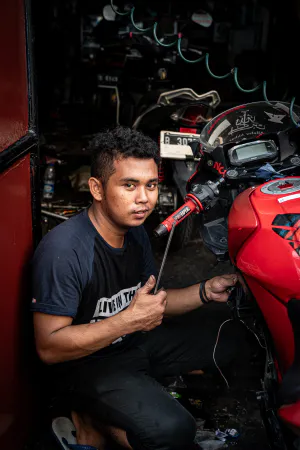 Young man maintaining a red motorbike