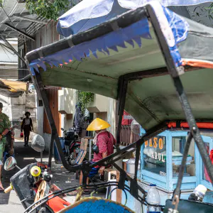 Becak, food stall, and people on the side of the road