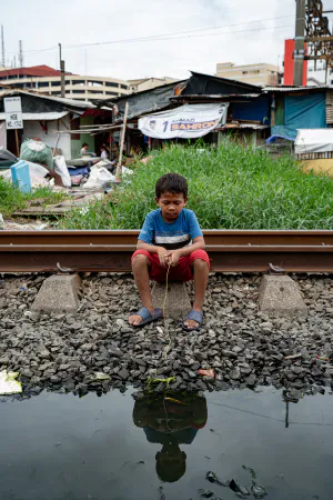 Boy sitting next to a puddle of water