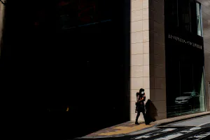 Woman walking in front of a shadowed building