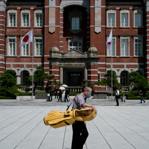 ゴルフバッグを抱えながら東京駅前を歩く男性