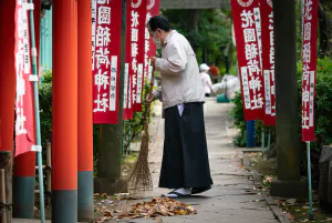 Priest sweeping the approach to Hanazono Inari Shrine with a broom