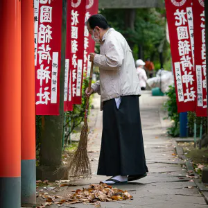 花園稲荷神社の参道を箒で掃く禰宜