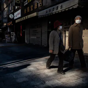 Old couple walking side by side wearing masks