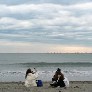 Two women sitting facing the sea
