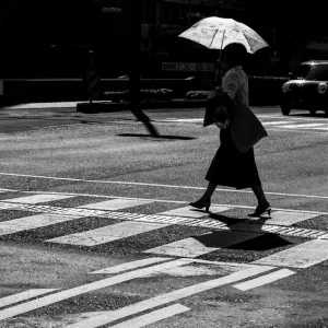 日傘を差して道を渡る女