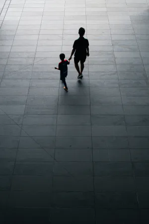 Silhouetted parent and child walking hand in hand