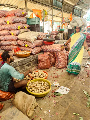 Woman with a load on her head and man selling potatoes