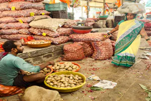 Woman with a load on her head and man selling potatoes