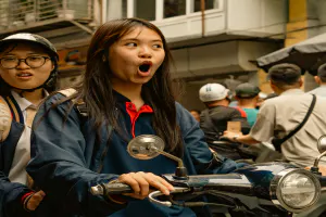 Girl riding off on a motorbike with her mouth wide open
