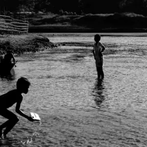 Silhouetted kids playing in river