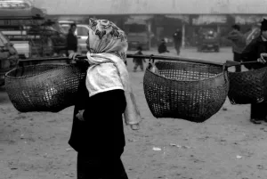 市場の中を天秤棒を担いで歩いていた女性