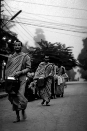 Buddhist monks walking dim street to ask fro alms