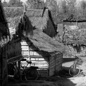 Young man walking between thatched huts