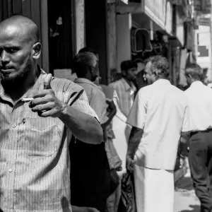 賑わっている道で親指を立てる男