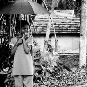 雨の中で傘を片手にウインクする女の子